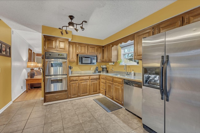 kitchen with sink, light tile patterned flooring, a textured ceiling, and stainless steel appliances