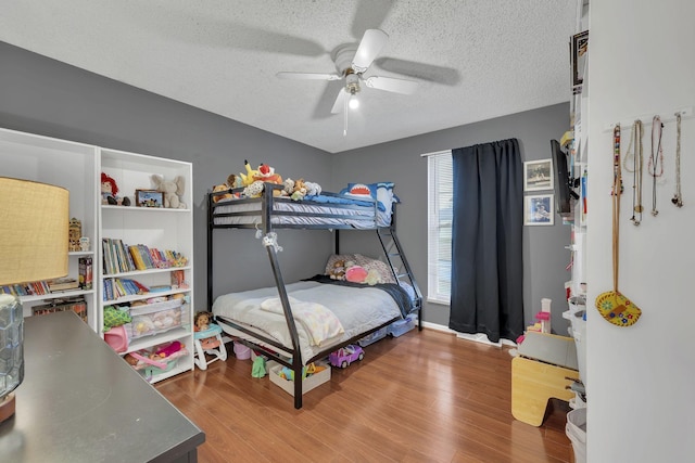 bedroom with ceiling fan, hardwood / wood-style floors, and a textured ceiling