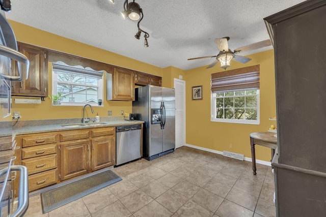 kitchen with ceiling fan, a textured ceiling, sink, stainless steel appliances, and light tile patterned flooring