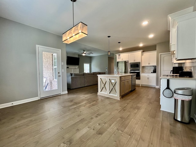 kitchen featuring white cabinetry, hanging light fixtures, decorative backsplash, an island with sink, and stainless steel appliances