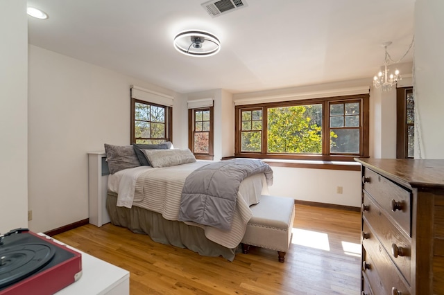 bedroom featuring light wood-type flooring, a notable chandelier, and multiple windows