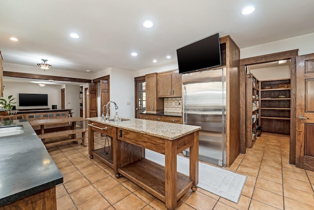 kitchen with light tile patterned floors, sink, tasteful backsplash, and stainless steel fridge