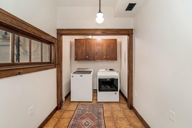 clothes washing area featuring washing machine and dryer, light tile patterned floors, and cabinets