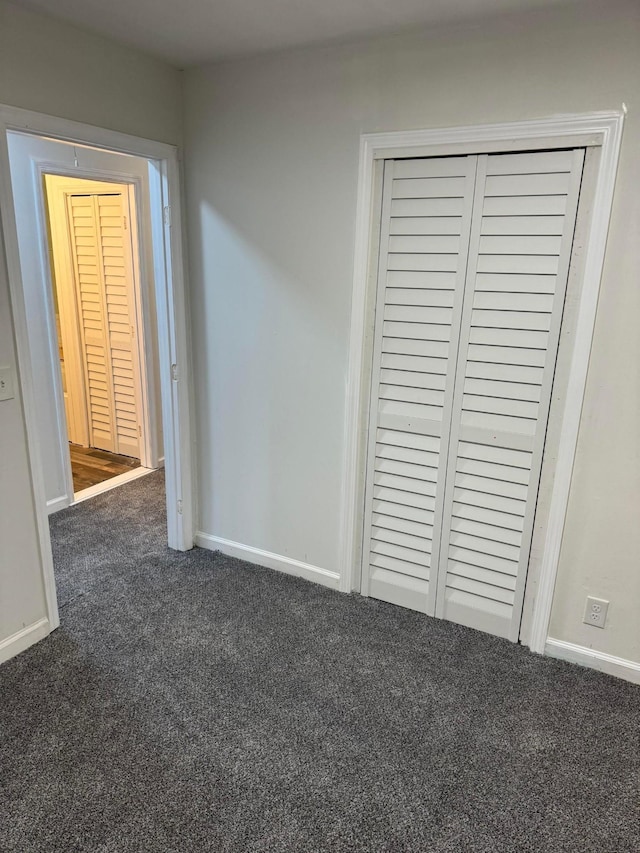 unfurnished bedroom featuring dark colored carpet and a closet