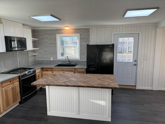 kitchen featuring black appliances, a center island, wood counters, white cabinetry, and sink