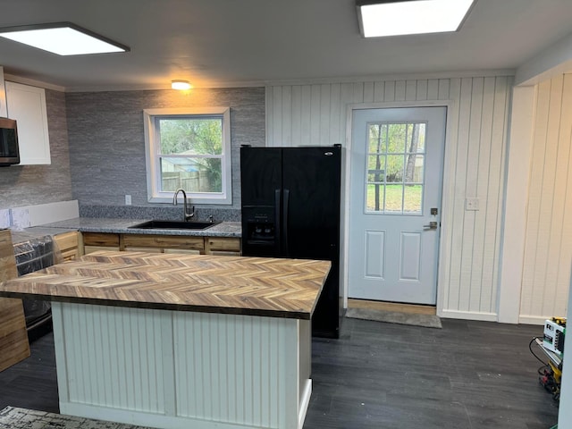 kitchen with black refrigerator with ice dispenser, white cabinetry, dark hardwood / wood-style flooring, sink, and butcher block countertops