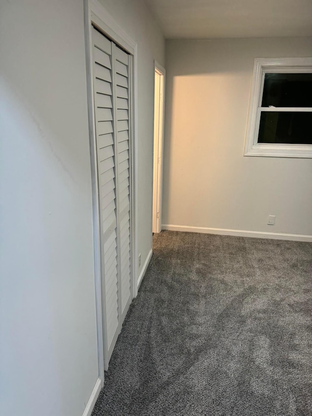 hall featuring dark colored carpet