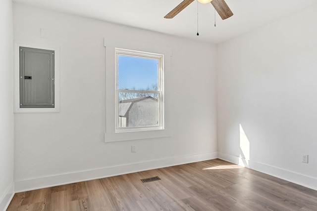 unfurnished room with hardwood / wood-style floors, electric panel, and ceiling fan