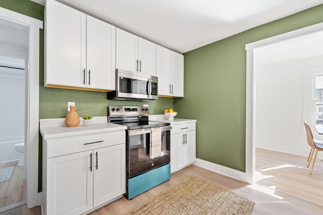 kitchen featuring light wood-type flooring, white cabinets, and appliances with stainless steel finishes