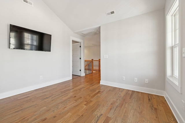 spare room with baseboards, visible vents, and wood finished floors