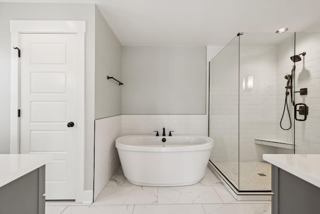 bathroom with marble finish floor, a shower stall, a freestanding bath, and vanity