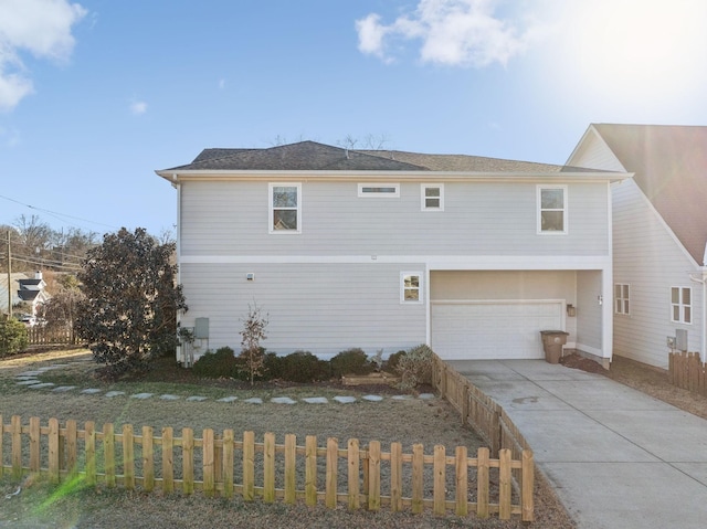 exterior space featuring an attached garage, a fenced front yard, and concrete driveway