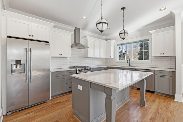 kitchen with a breakfast bar area, gray cabinetry, a sink, wall chimney exhaust hood, and high end appliances