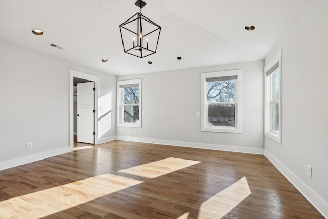 empty room with wood finished floors, visible vents, and a healthy amount of sunlight