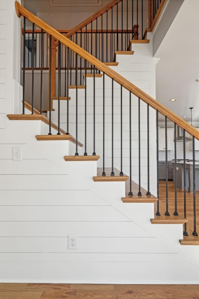 stairway with a high ceiling and wood finished floors