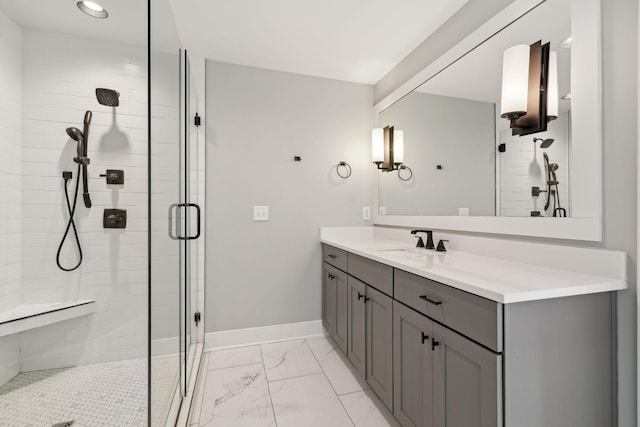 full bath featuring marble finish floor, a shower stall, baseboards, and vanity