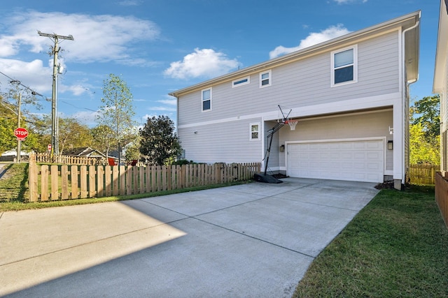 back of house featuring concrete driveway, fence, and an attached garage