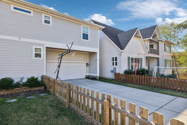 multi unit property featuring a garage, fence, driveway, and board and batten siding