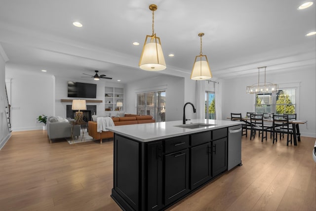 kitchen featuring pendant lighting, sink, dishwasher, and a center island with sink