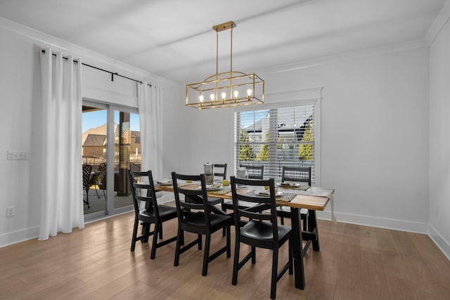 dining area with hardwood / wood-style flooring, crown molding, and an inviting chandelier