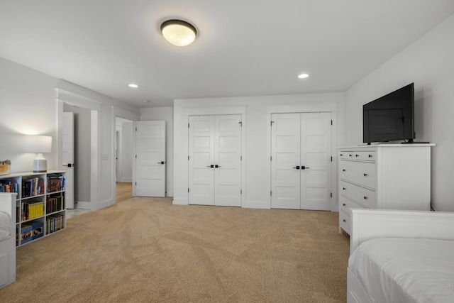 bedroom with light colored carpet and two closets