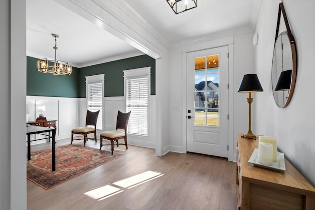 foyer entrance featuring ornamental molding, a chandelier, and light hardwood / wood-style flooring