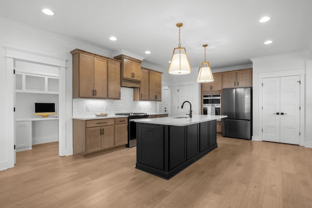 kitchen featuring hanging light fixtures, appliances with stainless steel finishes, sink, tasteful backsplash, and an island with sink