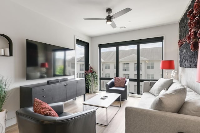 living room featuring a healthy amount of sunlight, light hardwood / wood-style flooring, and ceiling fan