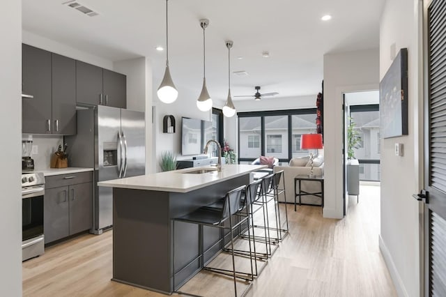 kitchen with appliances with stainless steel finishes, a kitchen island with sink, a kitchen breakfast bar, sink, and pendant lighting