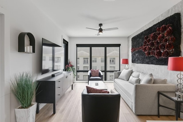 living room featuring light wood-type flooring, ceiling fan, and plenty of natural light