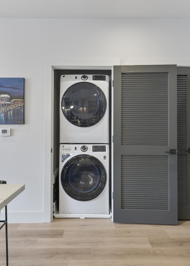 washroom with light hardwood / wood-style flooring and stacked washer and dryer