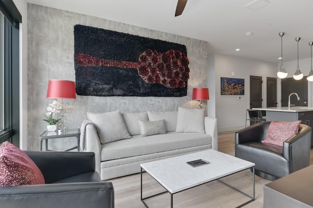 living room featuring ceiling fan, sink, and light hardwood / wood-style flooring