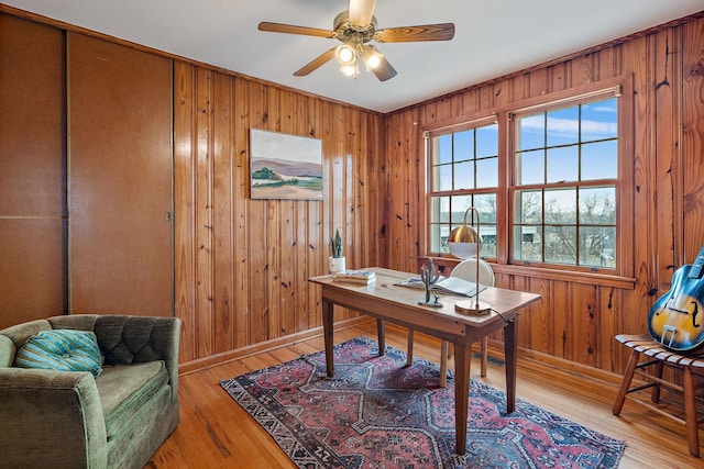 office area featuring wood walls, light hardwood / wood-style floors, and ceiling fan