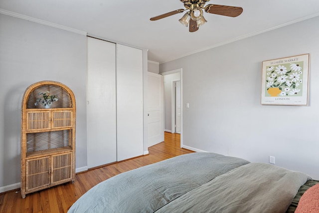 bedroom with light hardwood / wood-style floors, a closet, ceiling fan, and ornamental molding