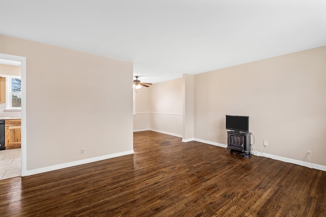 unfurnished living room with ceiling fan, a wood stove, and dark hardwood / wood-style floors