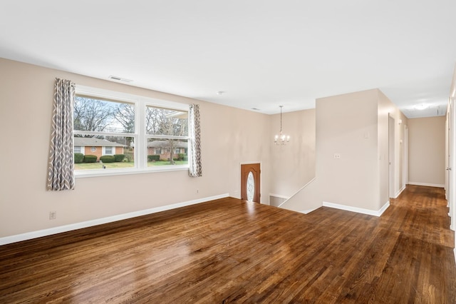 unfurnished room featuring an inviting chandelier and dark wood-type flooring