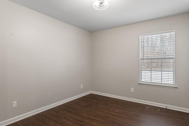 spare room featuring a wealth of natural light and dark hardwood / wood-style floors