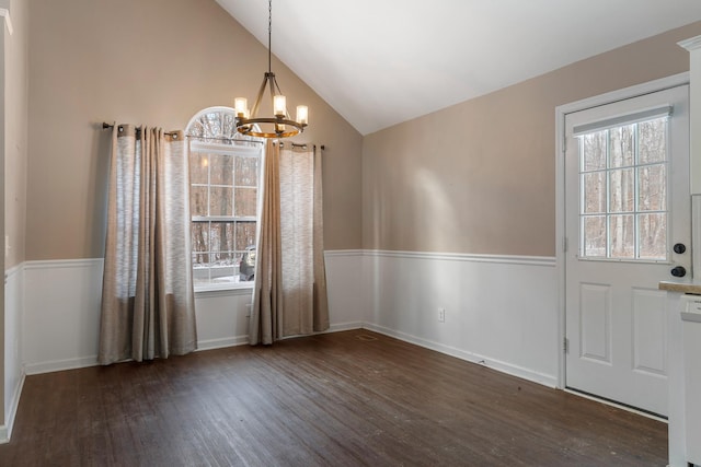 unfurnished dining area featuring dark hardwood / wood-style flooring, lofted ceiling, and a notable chandelier