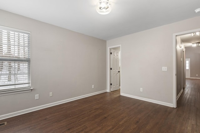 spare room with dark wood-type flooring and plenty of natural light