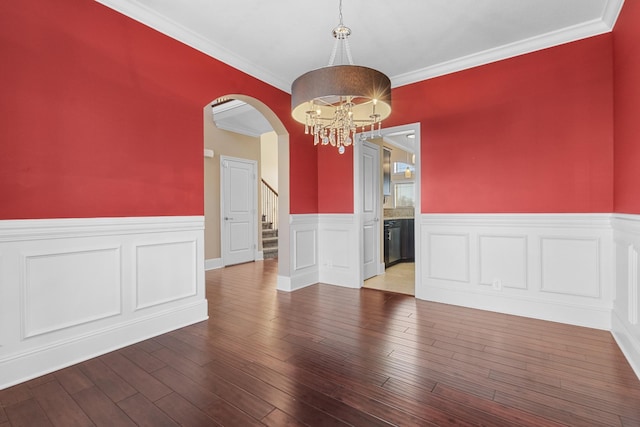 empty room featuring a notable chandelier, hardwood / wood-style floors, and crown molding