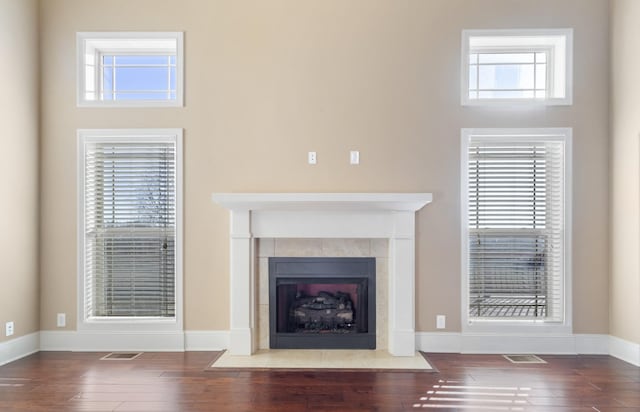 unfurnished living room featuring hardwood / wood-style flooring, a wealth of natural light, and a tiled fireplace