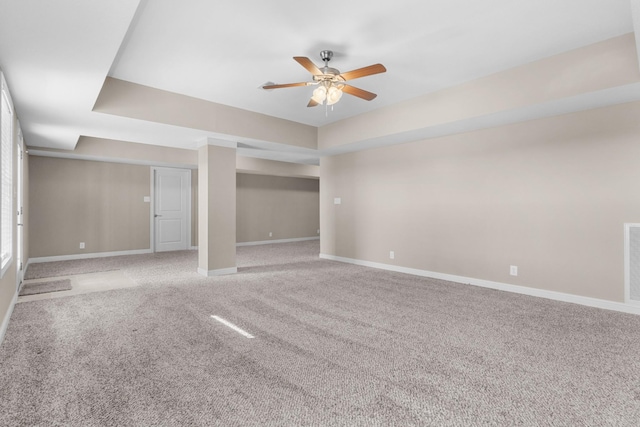 carpeted empty room featuring ceiling fan and a raised ceiling