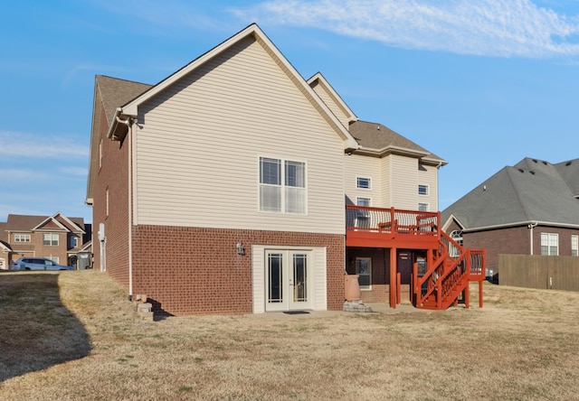 rear view of property featuring a wooden deck and a lawn