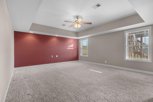 carpeted empty room featuring ceiling fan and a tray ceiling