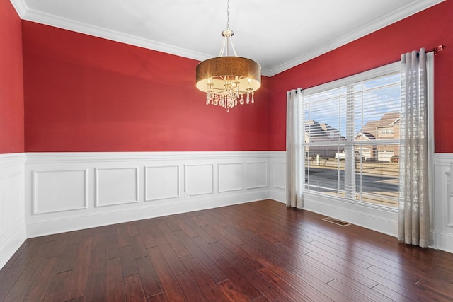 spare room with dark hardwood / wood-style flooring, ornamental molding, and an inviting chandelier