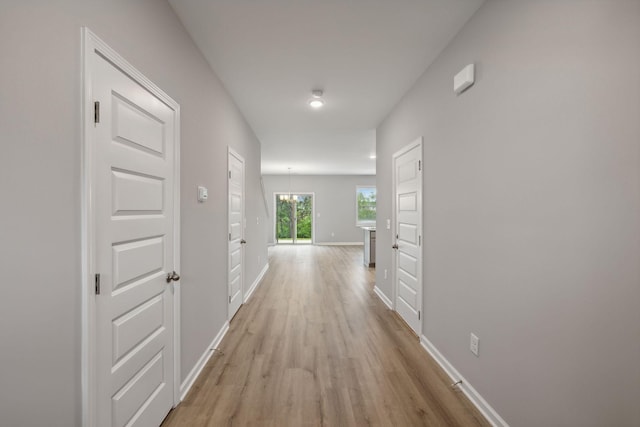 hall with baseboards and light wood-style floors