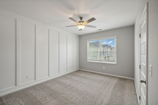 unfurnished bedroom with visible vents, a decorative wall, a ceiling fan, and carpet floors