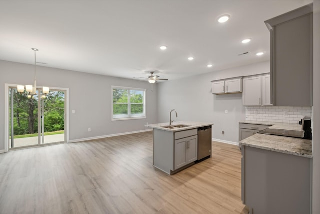 kitchen featuring light stone countertops, gray cabinetry, stainless steel dishwasher, sink, and backsplash