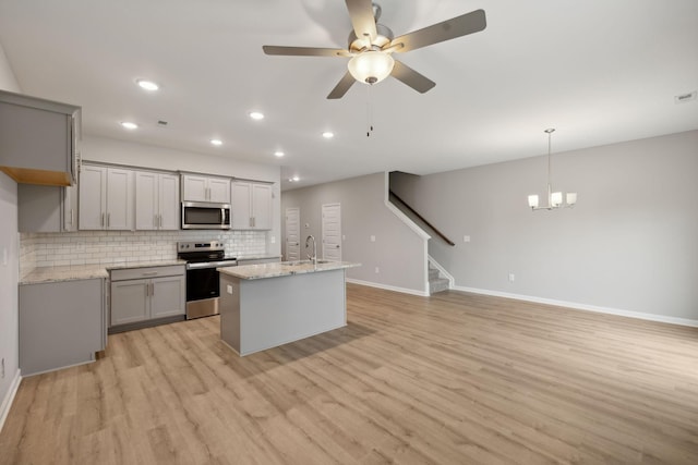 kitchen featuring light stone countertops, pendant lighting, appliances with stainless steel finishes, backsplash, and gray cabinetry