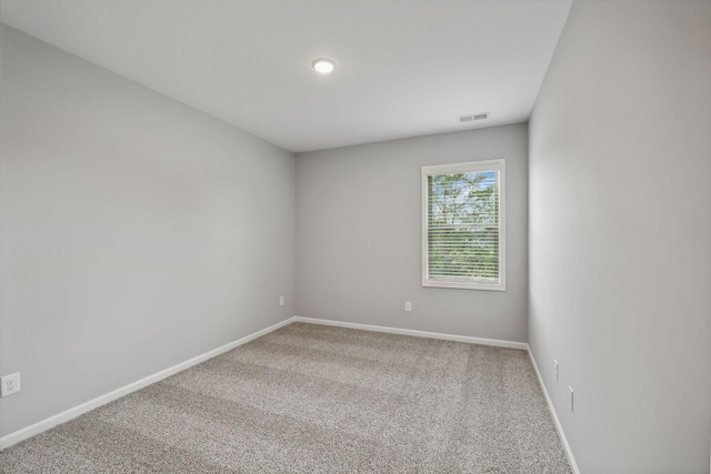 carpeted spare room featuring visible vents and baseboards